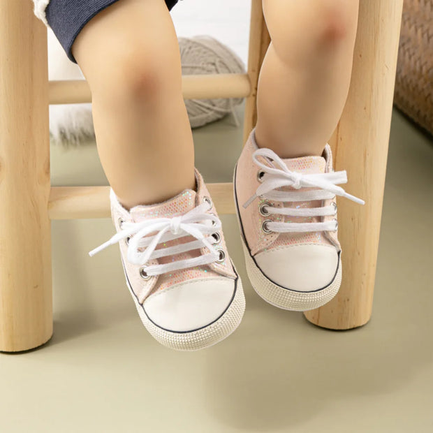 Children's pink sneakers with white laces on a neutral background