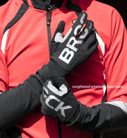 Black gloves with branding held by a person wearing a red jacket.
