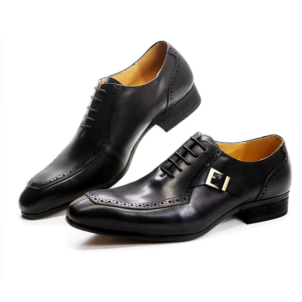 Pair of black dress shoes with a gold buckle on a white background