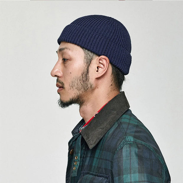 Man wearing a blue knit beanie and plaid jacket on a white background