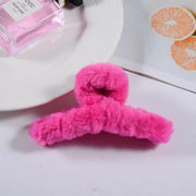 Pink fluffy hanger on a white surface with a pink bottle and orange slices in the background.