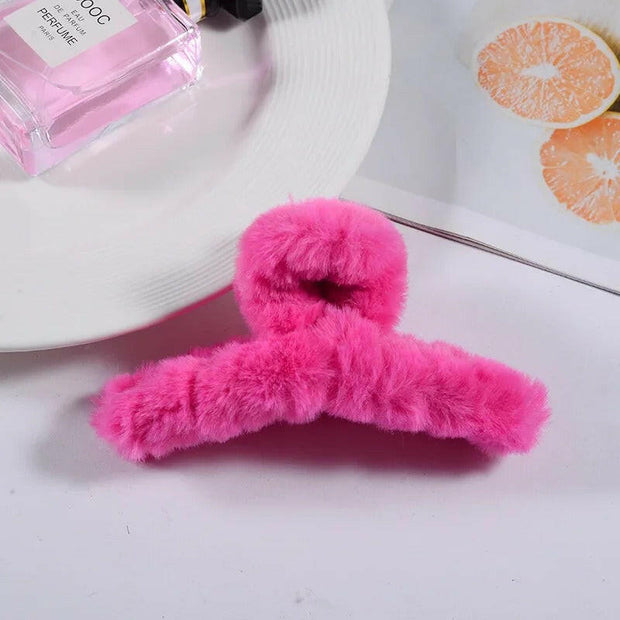 Pink fluffy hanger on a white surface with a pink bottle and orange slices in the background.
