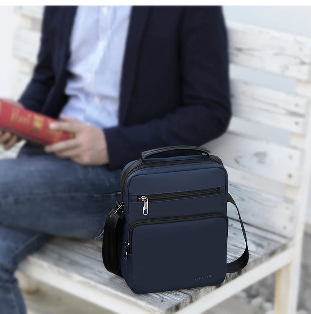 Navy blue backpack on a wooden bench with a person reading a book in the background