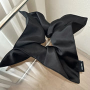 Black bow-shaped product on a light wooden surface with a neutral background