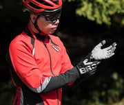 Person wearing a red cycling outfit with gloves and helmet, standing outdoors.