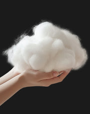 Hand holding a fluffy white cloud-like object against a black background