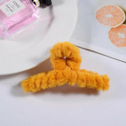 Yellow fluffy hanger on a white surface with a pink perfume bottle in the background.